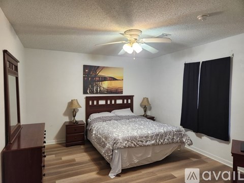 A bedroom with a bed, two lamps, and a painting on the wall.