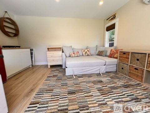 A bedroom with a bed, dresser, and a rug on the floor.