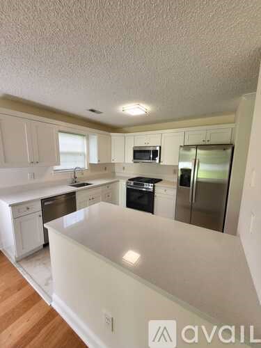 A kitchen with white cabinets and a white island.