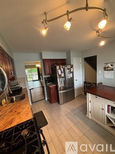 A kitchen with a black stove top oven and a refrigerator with a red door.