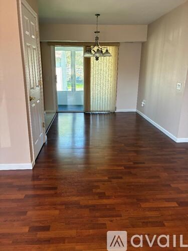 A room with wooden flooring and a chandelier.