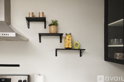 A kitchen with a stove, oven, and shelves with decorative items.
