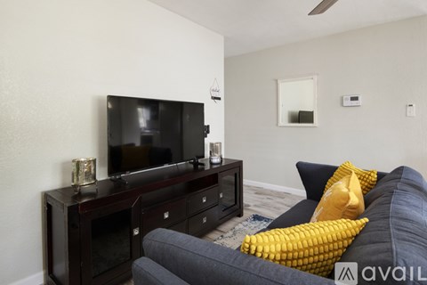 A living room with a grey couch and a black entertainment center.