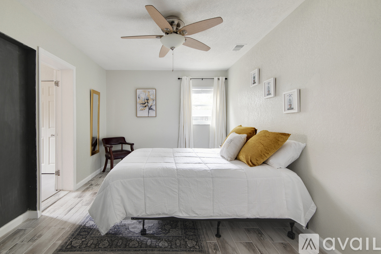 A bedroom with a white bed and a ceiling fan.