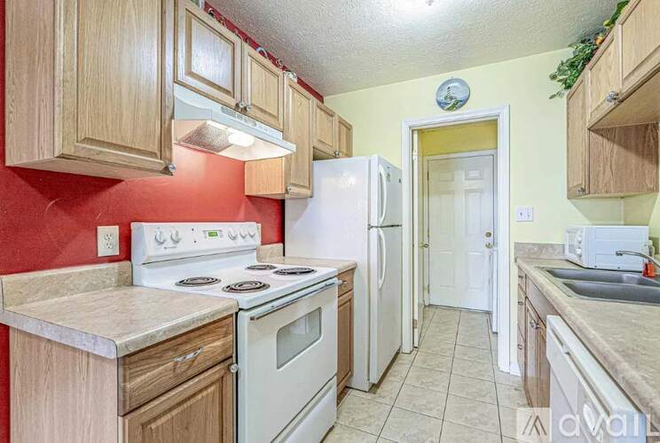 A kitchen with white appliances and wooden cabinets.