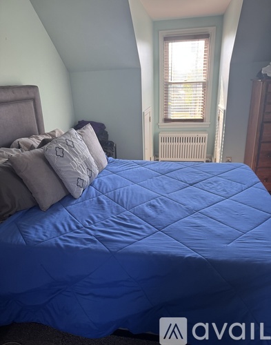 A blue comforter covers a bed in a room with a window.