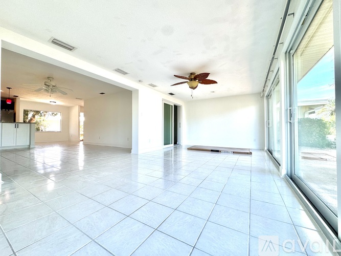 A spacious room with a ceiling fan and large windows.