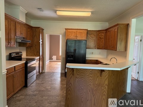 A kitchen with wooden cabinets and a black refrigerator.