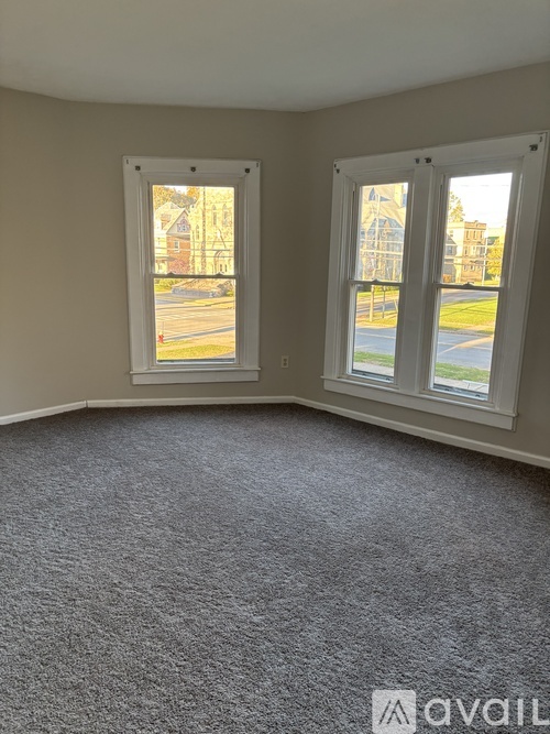 A room with two windows overlooking a street.
