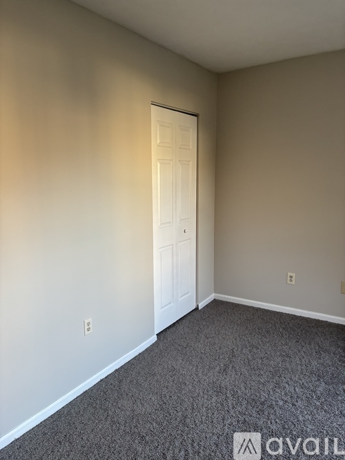 A room with a carpeted floor and a white door.
