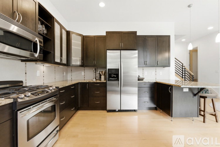 A modern kitchen with dark wood cabinets and stainless steel appliances.
