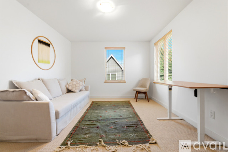 A living room with a couch, chair, rug, and a picture on the wall.