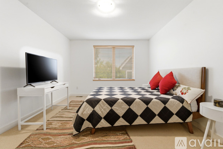 A bedroom with a bed, a television, and a window.