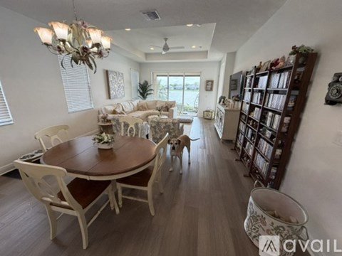 A dog is standing in a living room with a dining table and chairs.