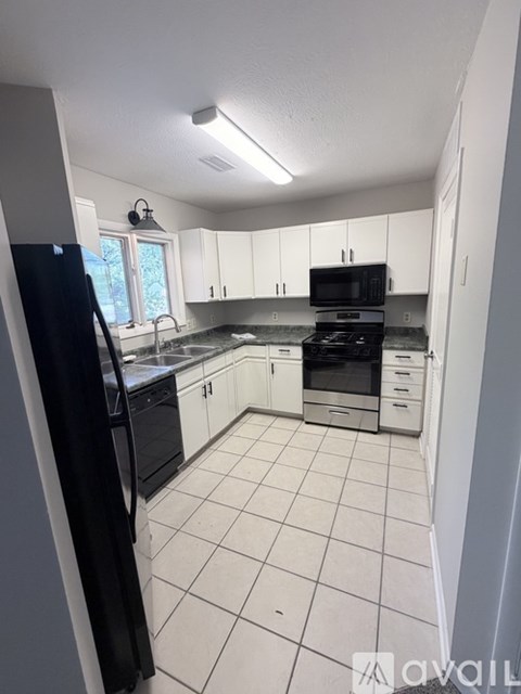 A kitchen with white cabinets and black appliances.