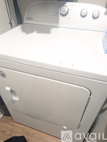 A white Whirlpool washing machine with a black bag on the floor.