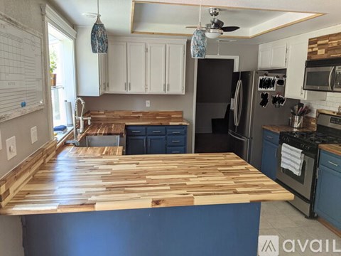 A kitchen with a wooden counter top and black appliances.