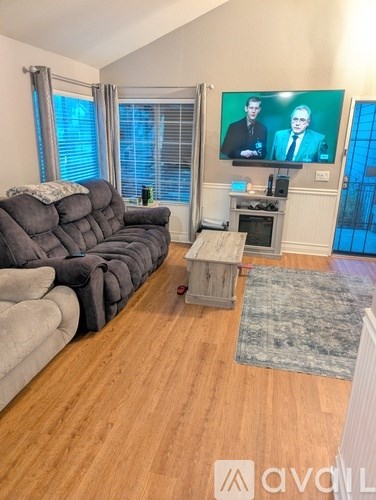 A living room with a grey sofa and a television on the wall.