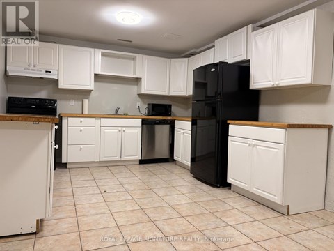 A kitchen with white cabinets and a black refrigerator.