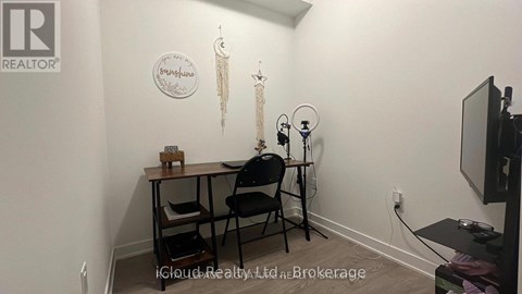 A room with a desk, chair, and a television.