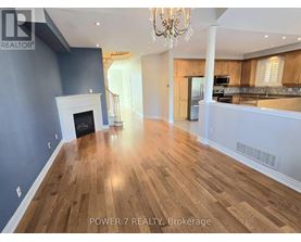 A spacious room with wooden flooring and a fireplace.