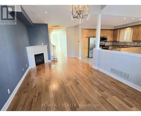 A spacious room with wooden flooring and a fireplace.