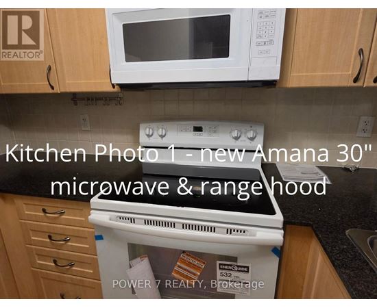 A kitchen with a new Amana 30" microwave and rangehood.
