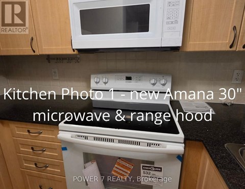 A kitchen with a new Amana 30" microwave and rangehood.