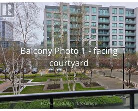 A view of a courtyard from a balcony with a building in the background.