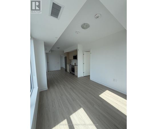 A well-lit, empty room with wooden flooring and white walls.