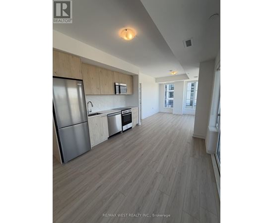 A kitchen with a refrigerator, oven, and sink.