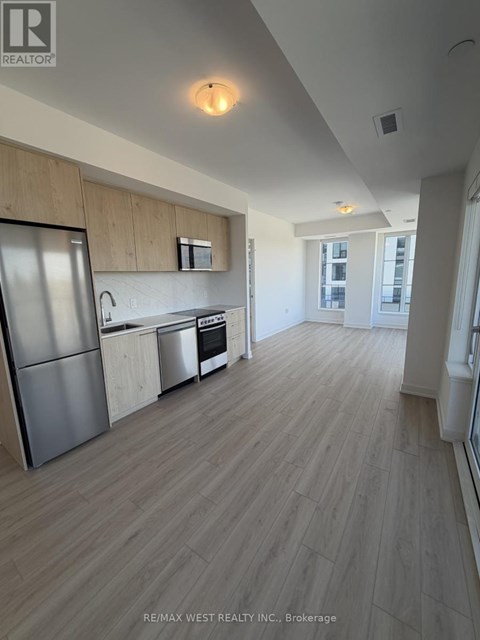 A kitchen with a refrigerator, oven, and sink.
