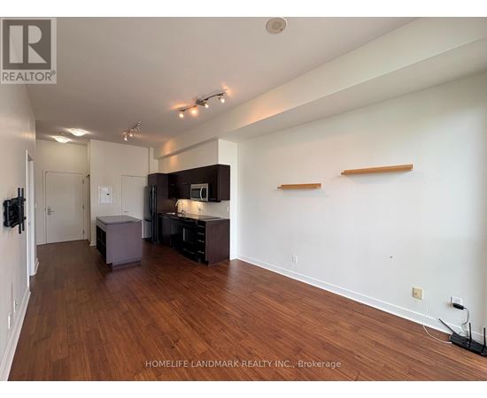 A spacious room with wooden floors and white walls, furnished with a kitchenette and a bar area.