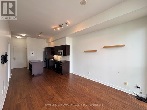 A spacious room with wooden floors and white walls, furnished with a kitchenette and a bar area.