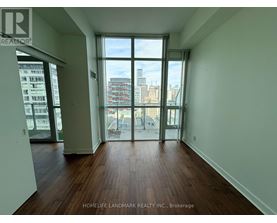 A room with wooden floors and a view of the city through large windows.