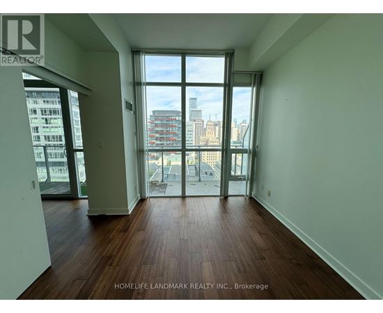 A room with wooden floors and a view of the city through large windows.