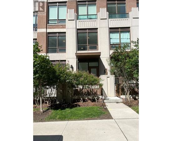 A building with a brown door and windows with trees in front.