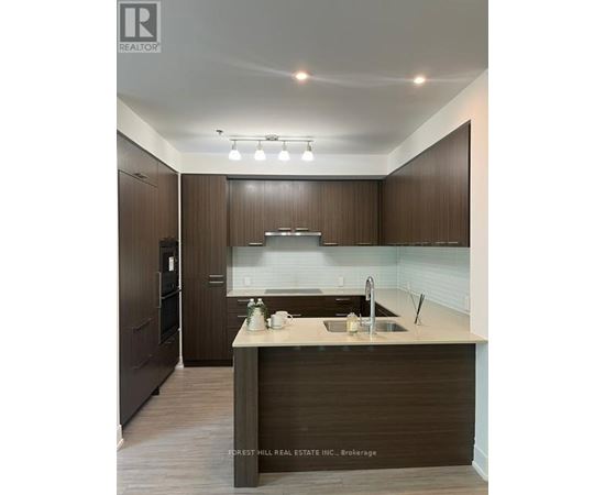 A modern kitchen with dark wood cabinets and a white countertop.