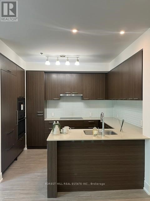 A modern kitchen with dark wood cabinets and a white countertop.
