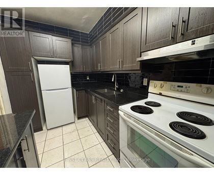 A kitchen with a white fridge, black countertops, and a white stove.
