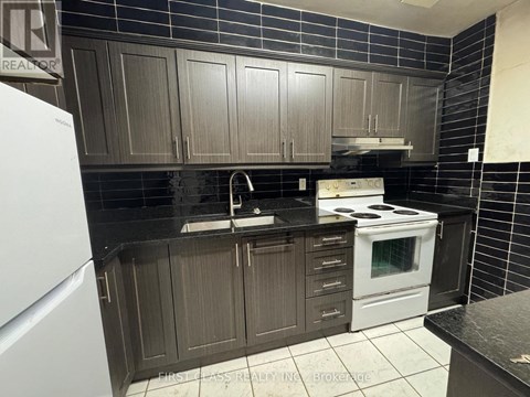 A kitchen with dark brown cabinets and a white stove.