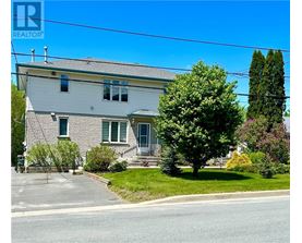 A house with a grey roof and green shutters is for sale.