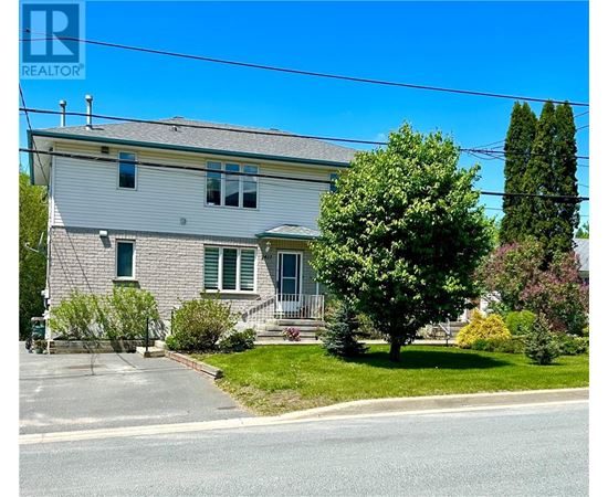 A house with a grey roof and green shutters is for sale.
