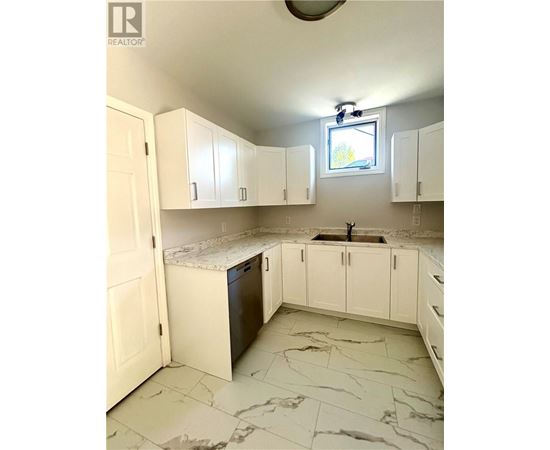 A kitchen with white cabinets and marble flooring.