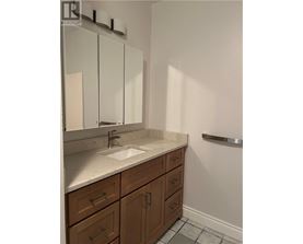 A bathroom with a sink, mirror, and wooden cabinets.