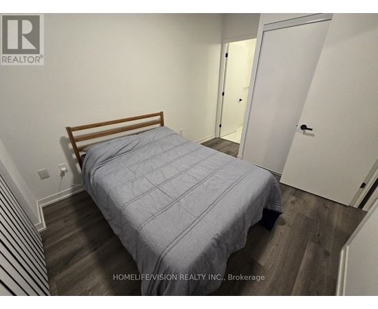 A bedroom with a bed, wooden headboard, and striped carpet.