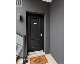A black door with a glass window on the left and a welcome mat on the right.