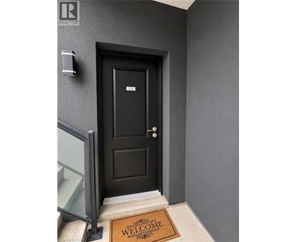 A black door with a glass window on the left and a welcome mat on the right.