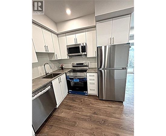 A kitchen with white cabinets and a stainless steel refrigerator.