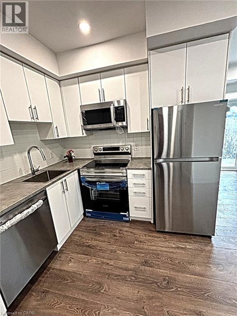 A kitchen with white cabinets and a stainless steel refrigerator.
